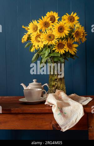 Sonnenblumenstrauß mit Teetasse und Topf in einem rustikalen Stilleben. Stockfoto