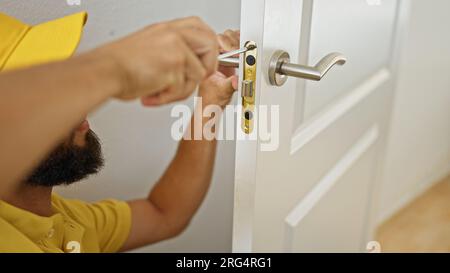 Junger hispano-Mann, der zu Hause eine Knopflose repariert Stockfoto