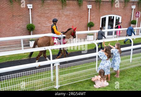 Kinder winken Jockey James Doyle zu, während er sich am 4. Tag des Qatar Goodwood Festival Meeting 2023 auf der Rennbahn Goodwood in Chichester auf Raasel aufmacht Stockfoto