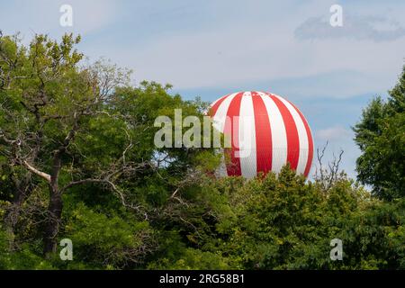Rot-weißer Ballon, der hinter Bäumen in Budapest, Ungarn, fliegt Stockfoto