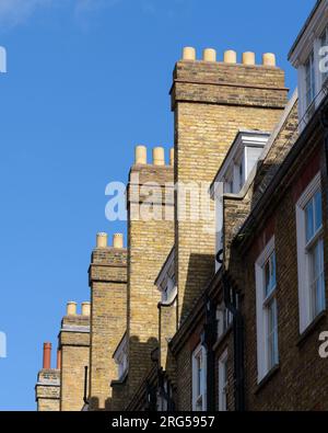 London, Großbritannien - 31. Juli 2023; hohe Ziegelschornsteine mit Töpfen auf Reihen von Reihenhäusern in London Stockfoto