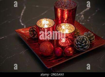 Rote weihnachtskerzen Dekoration auf dem Tisch. Entzündete Kerzen im Dunkeln. Stockfoto