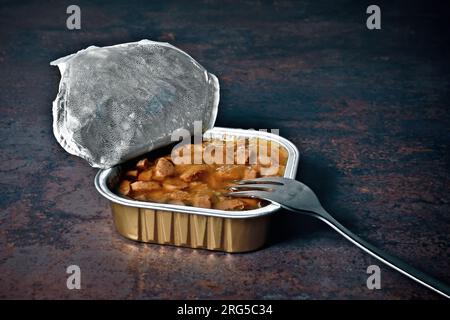 Öffnen Sie die Packung mit nassem Haustierfutter, und legen Sie die Gabel auf den Tisch. Stockfoto