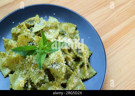 Köstliche Pasta mit Fliege oder Farfalle in Pesto-Sauce, serviert auf einem Holztisch Stockfoto