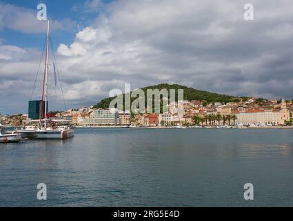 Die Uferpromenade der historischen Küstenstadt Split in Dalmatien, Kroatien. Der Marjan-Hügel liegt im Zentrum und die Kirche und das Kloster des Heiligen Franziskus sind ganz rechts Stockfoto