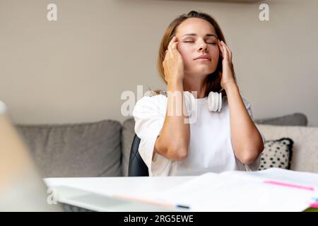 Frau mit Kopfschmerzen, überarbeitete Studentin, überstudiert und überarbeitetes Konzept. Stockfoto
