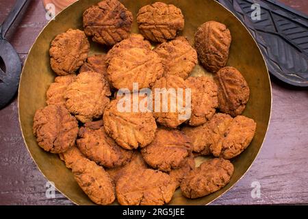 Thekua, ein indisches süßes Gericht oder Snacks auf einer Messingplatte mit Schimmel auf einem Holztisch. Es ist beliebt in bihar und jharkhand .Prashad in chhath Festival Stockfoto