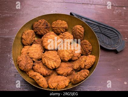 Thekua, ein indisches süßes Gericht oder Snacks auf einer Messingplatte mit Schimmel auf einem Holztisch. Es ist beliebt in bihar und jharkhand .Prashad in chhath Festival Stockfoto