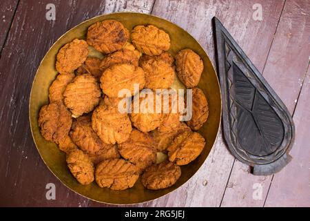 Thekua, ein indisches süßes Gericht oder Snacks auf einer Messingplatte mit Schimmel auf einem Holztisch. Es ist beliebt in bihar und jharkhand .Prashad in chhath Festival Stockfoto