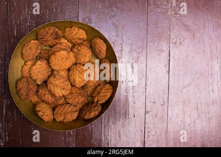 Thekua, ein indisches süßes Gericht oder Snacks auf einer Messingplatte mit Schimmel auf einem Holztisch. Es ist beliebt in bihar und jharkhand .Prashad in chhath Festival Stockfoto