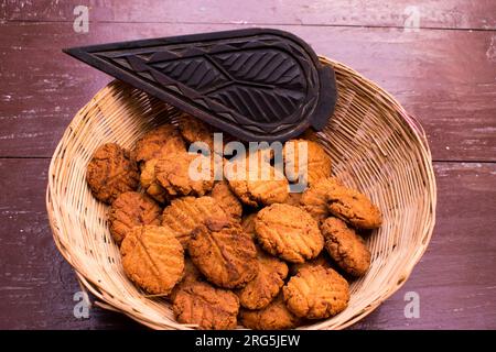 Thekua , ein indisches süßes Gericht oder Snacks in Bambus oder Holzkorb oder Tokri mit Schimmel auf einem Holztisch. Beliebt in bihar jharkhand. Prashad in Chath Stockfoto