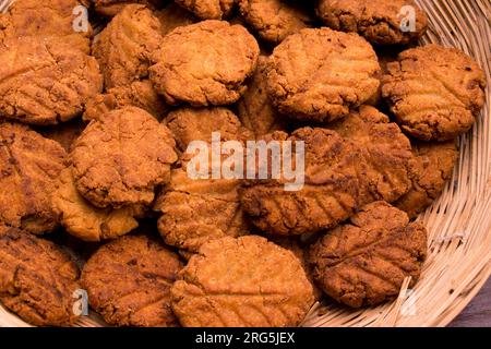 Thekua , ein indisches süßes Gericht oder Snacks in Bambus oder Holzkorb oder Tokri mit Schimmel auf einem Holztisch. Beliebt in bihar jharkhand. Prashad in Chath Stockfoto