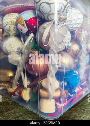 Farbenfrohe Weihnachtsbaumspielzeuge befinden sich in einer transparenten Kunststoffbox. Nahaufnahme. Selektiver Fokus. Stockfoto