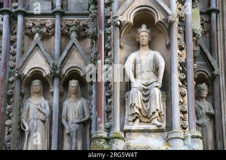 Die Statue eines mittelalterlichen Königs befindet sich inmitten der erodierten gotischen Statue und kunstvoll verzierten Schnitzereien auf dem nordwestlichen Turm der Wells Cathedral in Somerset. England. Stockfoto