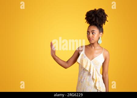 Unzufriedene, selbstbewusste, beleidigte, kleidende Millenial-schwarze Dame macht mit der Hand Halt Stockfoto