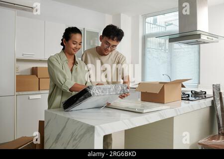 Fröhliches Paar, das gerahmte Fotos einpackt und einpackt, wenn es auszieht Stockfoto