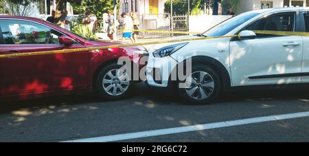 Zwei frontal abgestürzte schwarz-weiße Autos auf der Straße, schwarz auf der entgegenkommenden Spur Stockfoto
