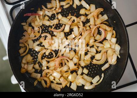 Schalotten-Zwiebeln in einer Pfanne auf einem Gasherd braten Stockfoto