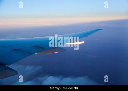 Das erste Sonnenlicht reflektiert von einem Flugzeugflügel während des Fluges über den Nahen Osten. Stockfoto