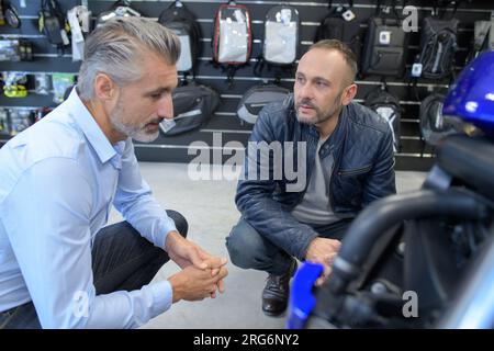 Kunde und Verkäufer diskutieren Motorrad beim Motorradhändler Stockfoto
