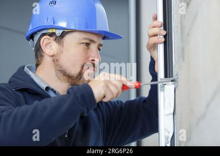 Junger männlicher Arbeiter, der Wand bumst Stockfoto