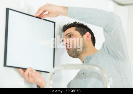 Mann, der ein Bild an die Wand legt Stockfoto