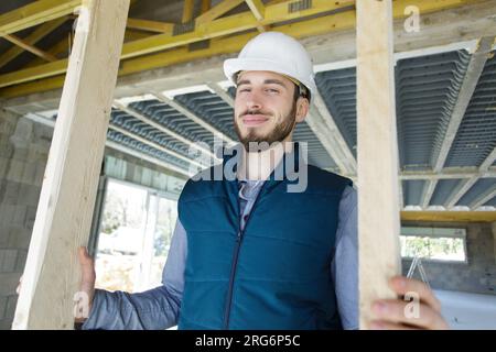 Männlicher Bauunternehmer, der einen Türrahmen aus Holz hält Stockfoto