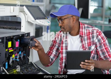 Servicemitarbeiter mit Tisch, der den Büro-Fotokopierer pflegt Stockfoto