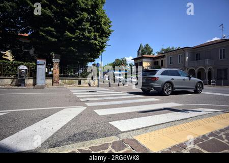 Kreuzung in einem Dorf in der italienischen Landschaft mit vorbeifahrenden Autos von einem Gehweg aus gesehen Stockfoto