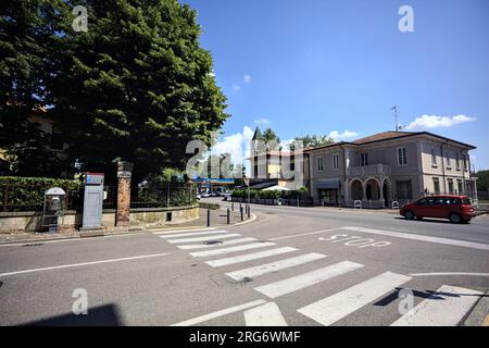 Kreuzung in einem Dorf in der italienischen Landschaft mit vorbeifahrenden Autos von einem Gehweg aus gesehen Stockfoto