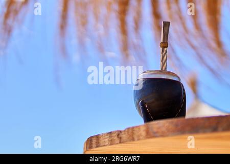 Das goldstück auf dem Holztisch mit blauem Himmel im Hintergrund und einem Strohschirm oben auf dem Tisch paaren. Speicherplatz kopieren Stockfoto