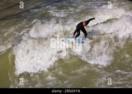 MÜNCHEN, DEUTSCHLAND - 07. APRIL: Surfer surft am Isar in riesigen Wellen zur Saisoneröffnung an der Wittelsbacher Brücke im Herzen Münchens am April Stockfoto