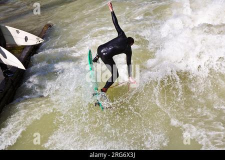 MÜNCHEN, DEUTSCHLAND - 07. APRIL: Surfer surft am Isar in riesigen Wellen zur Saisoneröffnung an der Wittelsbacher Brücke im Herzen Münchens am April Stockfoto