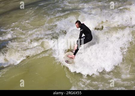 MÜNCHEN, DEUTSCHLAND - 07. APRIL: Surfer surft am Isar in riesigen Wellen zur Saisoneröffnung an der Wittelsbacher Brücke im Herzen Münchens am April Stockfoto