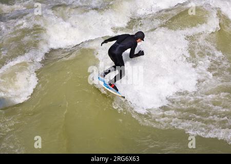 MÜNCHEN, DEUTSCHLAND - 07. APRIL: Surfer surft am Isar in riesigen Wellen zur Saisoneröffnung an der Wittelsbacher Brücke im Herzen Münchens am April Stockfoto