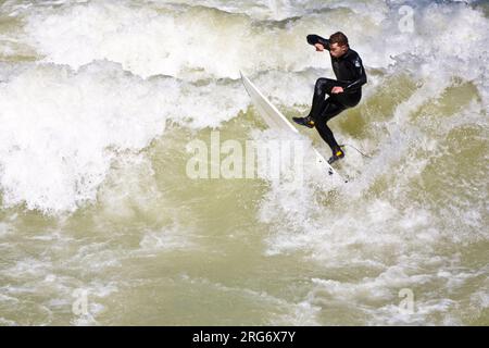 MÜNCHEN, DEUTSCHLAND - 07. APRIL: Surfer surft am Isar in riesigen Wellen zur Saisoneröffnung an der Wittelsbacher Brücke im Herzen Münchens am April Stockfoto