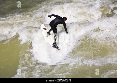 MÜNCHEN, DEUTSCHLAND - 07. APRIL: Surfer surft am Isar in riesigen Wellen zur Saisoneröffnung an der Wittelsbacher Brücke im Herzen Münchens am April Stockfoto