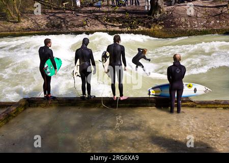 MÜNCHEN, DEUTSCHLAND - 07. APRIL: Surfer surft am Isar in riesigen Wellen zur Saisoneröffnung an der Wittelsbacher Brücke im Herzen Münchens am April Stockfoto