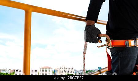 Bauarbeiter mit Sicherheitsgurt und Sicherheitsleitung arbeiten an Ein hohes Hotel Stockfoto