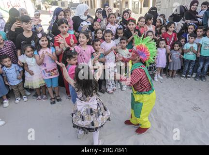 Gaza-Stadt, Palästina. 07. Aug. 2023. Ein als Clown verkleideter palästinensischer Mann führt im Flüchtlingslager Jabalia im nördlichen Gazastreifen unter den hohen Temperaturen und Stromausfällen während der andauernden israelischen Blockade Unterhaltungsaktivitäten für Kinder durch. Für die Palästinenser, die im überfüllten Gazastreifen leben, wurde die schwelende Sommerhitze durch die durch die anhaltende israelische Blockade verursachten Stromausfälle noch verschärft. (Foto: Mahmoud Issa/SOPA Images/Sipa USA) Guthaben: SIPA USA/Alamy Live News Stockfoto