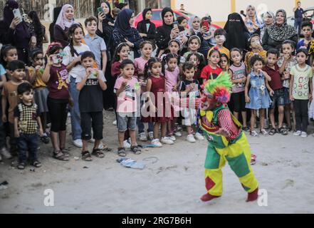 Gaza-Stadt, Palästina. 07. Aug. 2023. Ein als Clown verkleideter palästinensischer Mann führt im Flüchtlingslager Jabalia im nördlichen Gazastreifen unter den hohen Temperaturen und Stromausfällen während der andauernden israelischen Blockade Unterhaltungsaktivitäten für Kinder durch. Für die Palästinenser, die im überfüllten Gazastreifen leben, wurde die schwelende Sommerhitze durch die durch die anhaltende israelische Blockade verursachten Stromausfälle noch verschärft. (Foto: Mahmoud Issa/SOPA Images/Sipa USA) Guthaben: SIPA USA/Alamy Live News Stockfoto