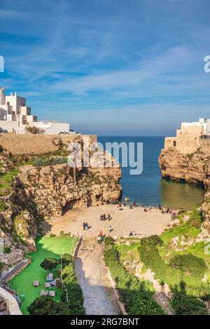 Polignano a Mare, Italien - 2. Januar 2023: Lama Monachile, eine kompakte Bucht, bekannt für ihr klares Wasser und den Kieselstrand, flankiert von dramatischen, zerklüfteten Klippen. Stockfoto