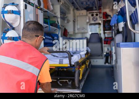 Rückansicht eines männlichen Angehörigen des medizinischen Personals, der eine Bahre aus einem Krankenwagen nimmt Stockfoto