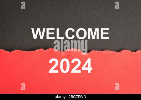 Willkommen 2024, Nachricht auf schwarz-rotem Papier. Neujahrskonzept. Stockfoto
