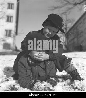 Schnee und Winter in alten Zeiten. Zwei Jungs im Schnee, wo einer von ihnen die Oberhand hatte. Mit einer Hand voll Schnee reibt er seinen Freund mit dem Schnee im Gesicht. Ein unbeliebtes Phänomen, das von einer beteiligten Partei gesehen wird, dass jemand anderes Schnee ins Gesicht gestoßen hat, ohne sich selbst verteidigen zu können. Schweden 1944. Kristoffersson Ref. M35-1 Stockfoto