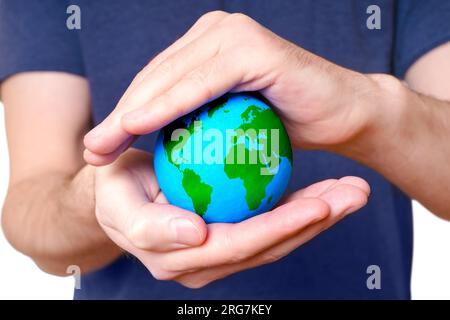 Der kleine grüne und blaue Globus ist zwischen gehüllten Händen umschlossen, die als Schutz dienen und die Notwendigkeit unterstreichen, unsere Umwelt zu schützen und a s zu fördern Stockfoto