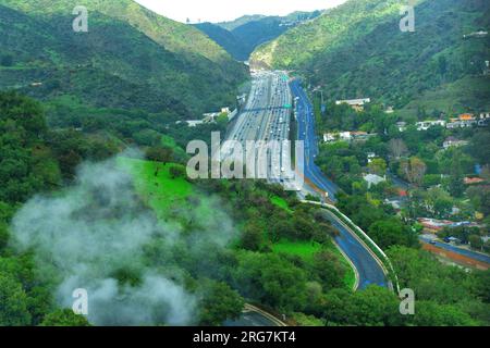 Blick vom Getty Center auf einen geschäftigen Highway, eingebettet zwischen üppigem Grün der Hügel. Stockfoto