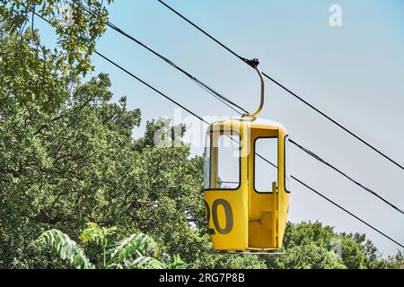 Gelbe Kabine der Seilbahn vor dem sonnenbeleuchteten blauen Himmel. Touristenattraktion im Vergnügungspark für ankommende Besucher im Resort Stockfoto