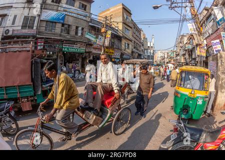 Neu Delhi, Indien - 17. November 2011: Im alten Delhi, Chawri Bazaar, trägt der Mensch Fracht und Menschen mit seiner Rikscha. Stockfoto