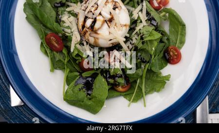 Frischer, gesunder Salat aus Rucola und Burrata mit Dressing. Draufsicht. Stockfoto